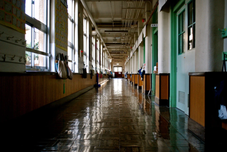 Older school hallway with big windows and a shiny floor.