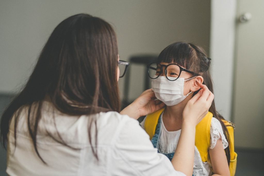 Adult putting a mask on a young child.