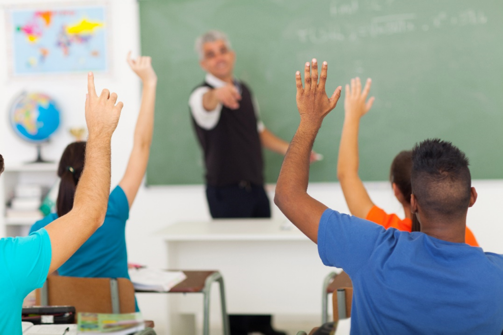 Students eagerly raising hands in class.